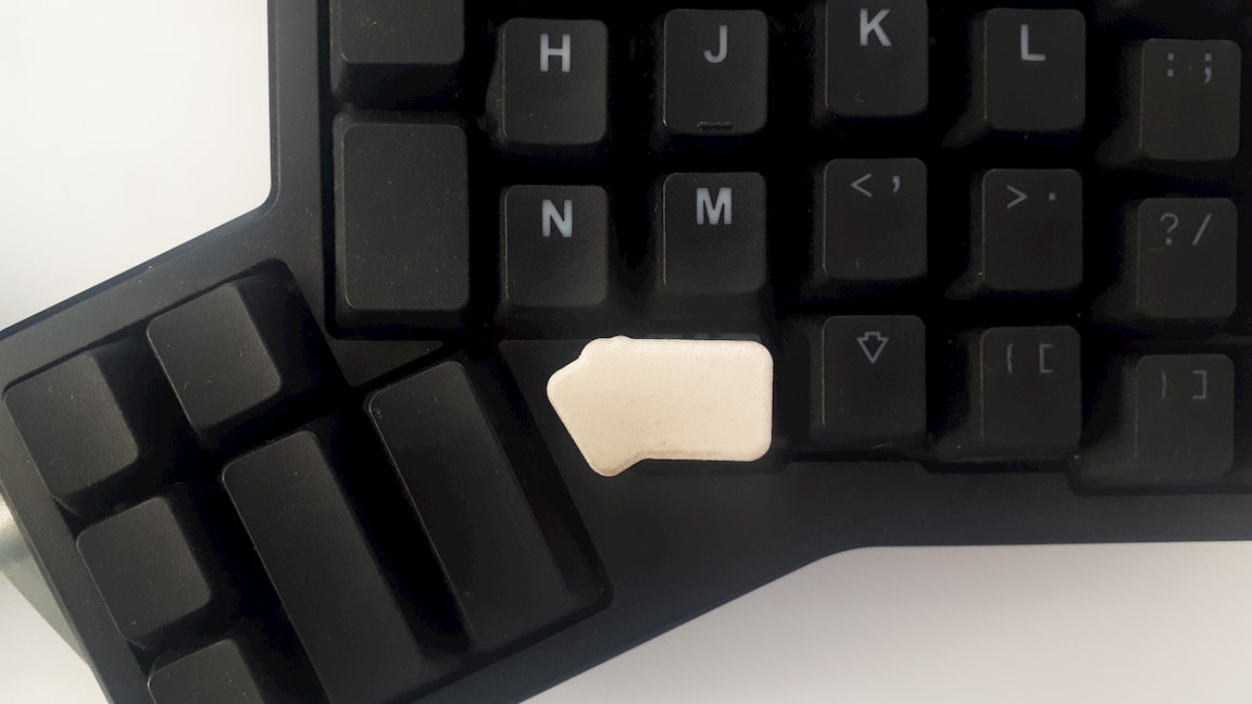 A custom, 3D printed keycap. Standing out on the keyboard, just before the thumb clusters.